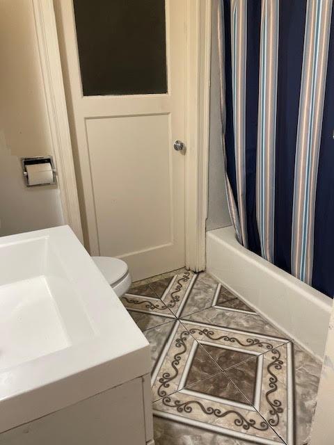 full bathroom with shower / tub combo, toilet, tile patterned flooring, and vanity