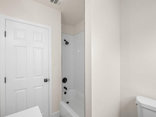 bathroom with toilet and tiled shower / bath combo