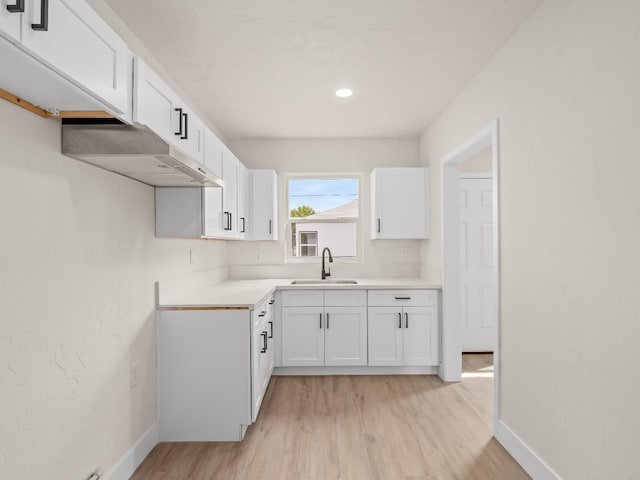 kitchen with white cabinets, sink, light hardwood / wood-style floors, and range hood