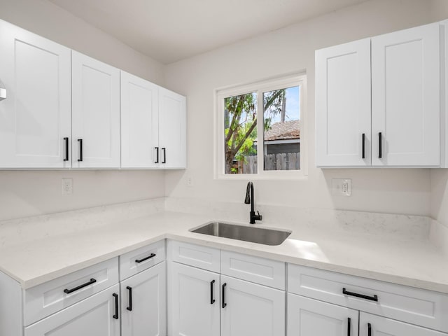 kitchen featuring sink, white cabinets, and light stone countertops