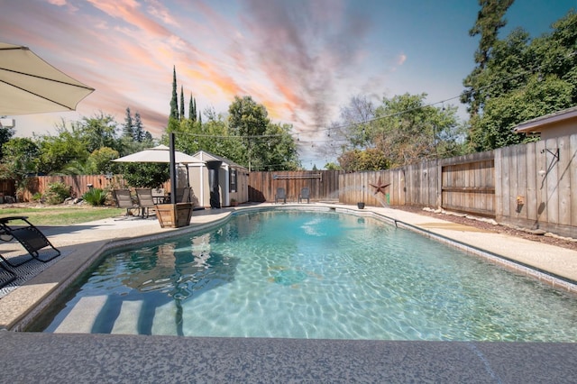 pool at dusk with a patio, a fenced backyard, and a fenced in pool