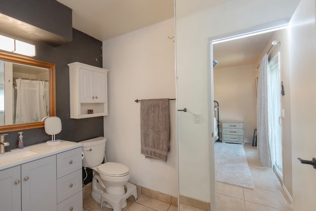 bathroom with toilet, vanity, baseboards, and tile patterned floors