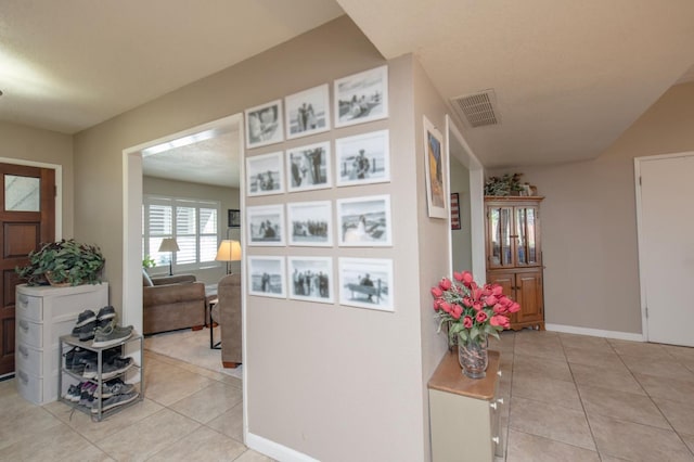 corridor featuring light tile patterned flooring, visible vents, and baseboards