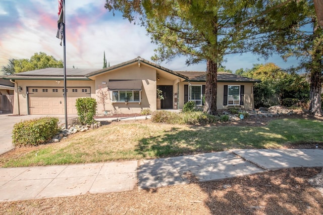 ranch-style house featuring an attached garage, driveway, a lawn, and stucco siding