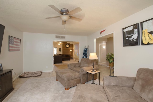 living area with ceiling fan, light tile patterned floors, a textured ceiling, visible vents, and baseboards