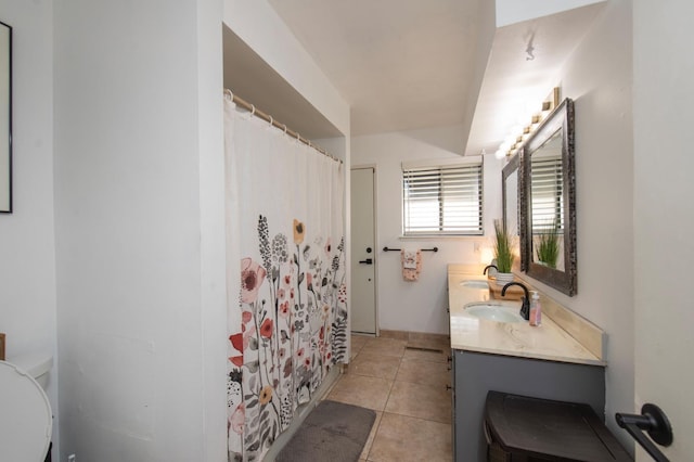 bathroom with curtained shower, double vanity, a sink, and tile patterned floors