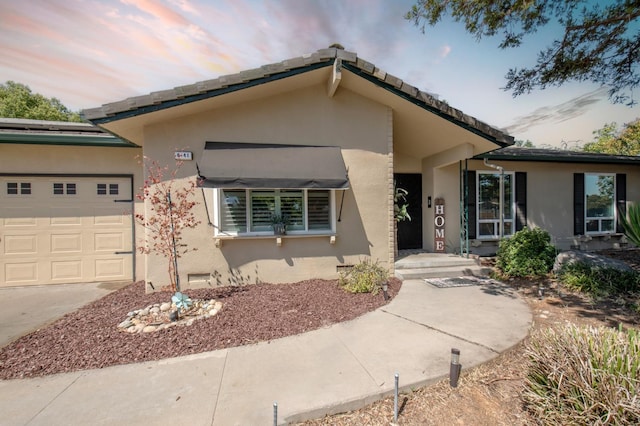 ranch-style home featuring a garage, concrete driveway, and stucco siding