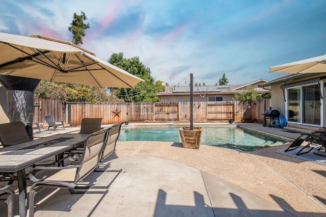 view of swimming pool featuring grilling area, a patio area, a fenced backyard, and a fenced in pool