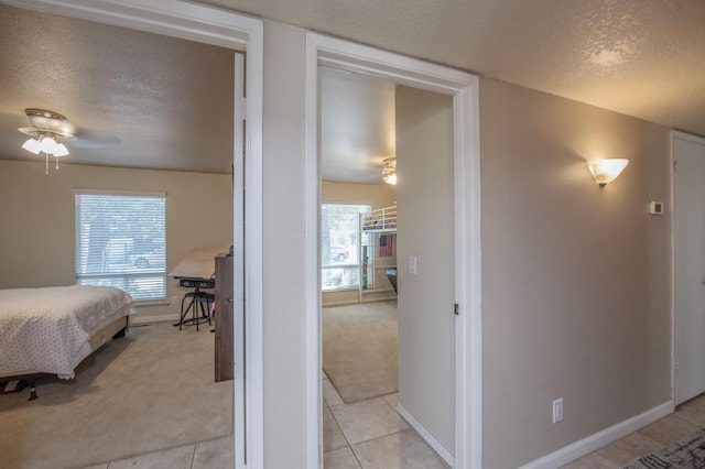 bedroom featuring light carpet, a textured ceiling, and baseboards