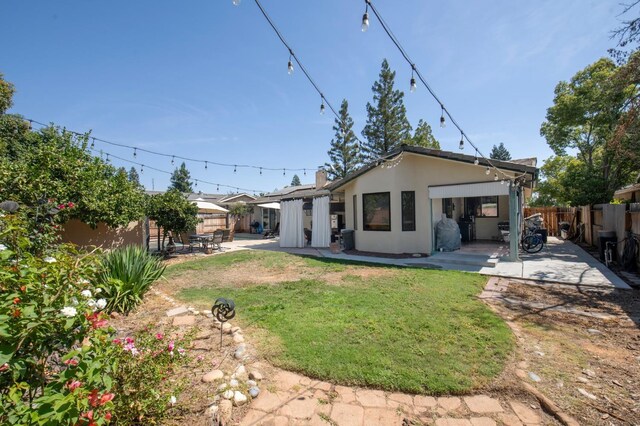 back of house featuring a patio, fence, a lawn, and stucco siding