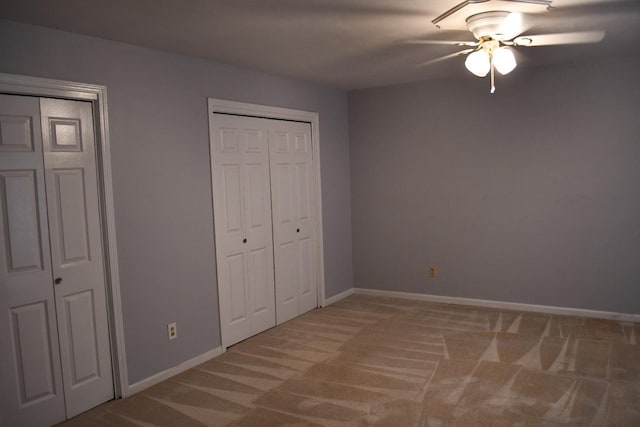 unfurnished bedroom featuring ceiling fan, two closets, and carpet