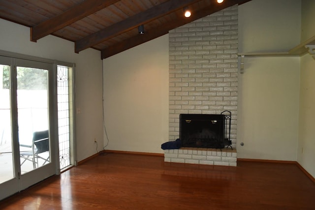 unfurnished living room featuring lofted ceiling with beams, hardwood / wood-style floors, brick wall, and a fireplace