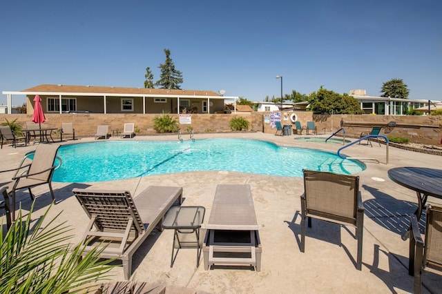 pool featuring fence, a hot tub, and a patio area