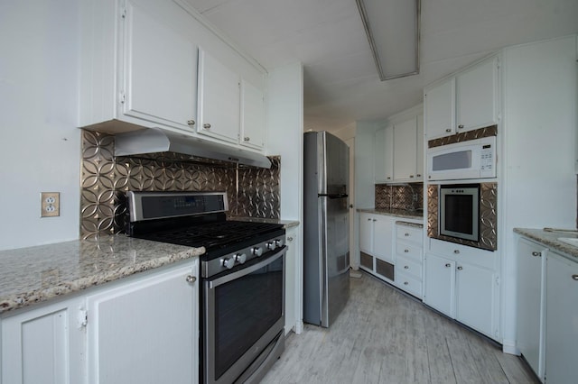 kitchen featuring under cabinet range hood, white cabinets, tasteful backsplash, and appliances with stainless steel finishes