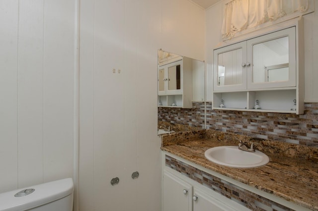 half bath featuring vanity, toilet, and backsplash