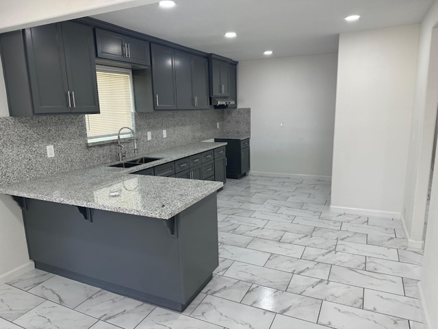 kitchen with light stone countertops, sink, light tile patterned flooring, a breakfast bar area, and tasteful backsplash