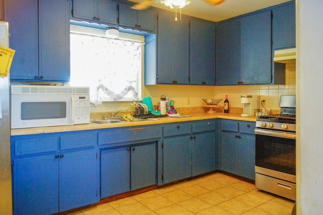 kitchen with stainless steel gas stove, backsplash, sink, ceiling fan, and blue cabinets