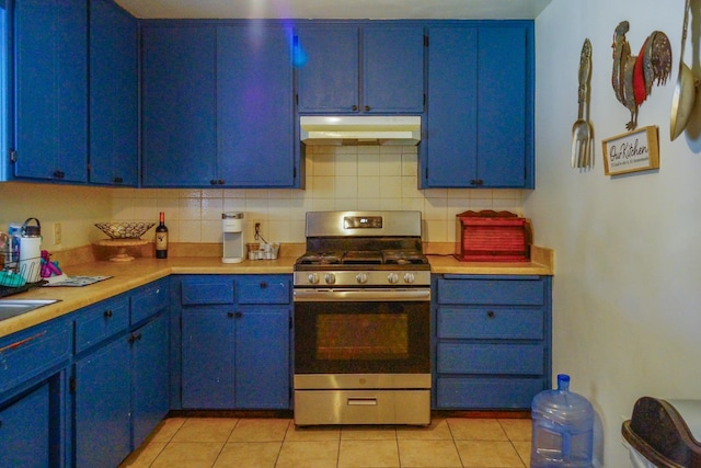 kitchen featuring backsplash, light tile patterned floors, stainless steel range with gas cooktop, and blue cabinetry