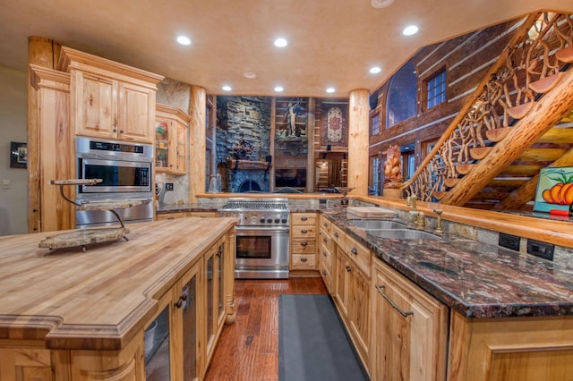 kitchen with wooden counters, light brown cabinetry, sink, dark hardwood / wood-style floors, and appliances with stainless steel finishes