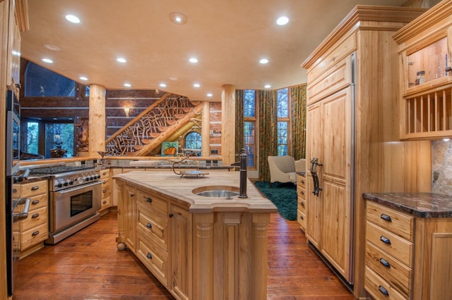 kitchen with stainless steel range, hardwood / wood-style flooring, and an island with sink