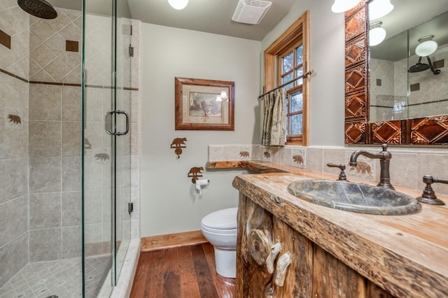 bathroom featuring toilet, a shower with door, vanity, backsplash, and wood-type flooring