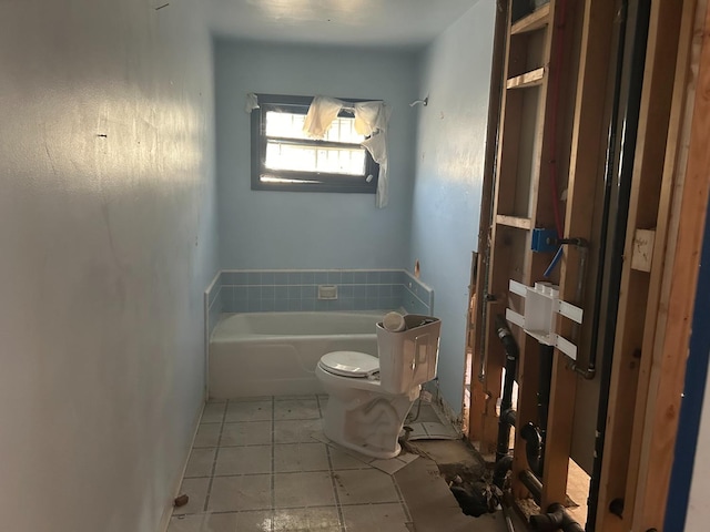 bathroom with a tub to relax in, toilet, and tile patterned floors