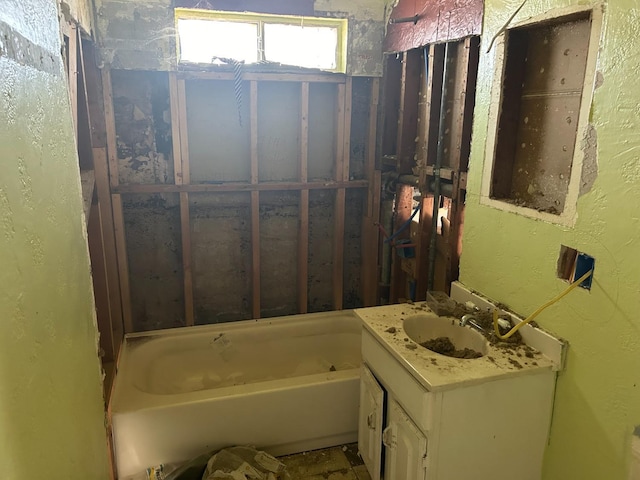 bathroom with a textured wall, a bathing tub, and vanity