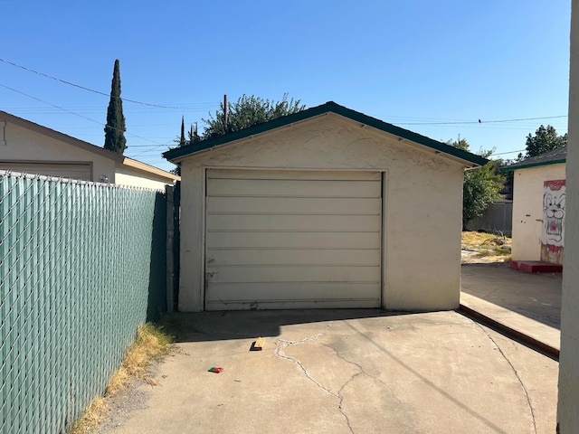 detached garage with concrete driveway and fence