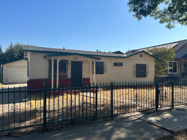 view of front of house with a fenced front yard, an outbuilding, and stucco siding