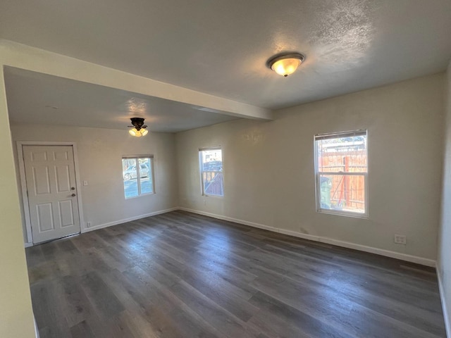 unfurnished room featuring beamed ceiling, dark hardwood / wood-style floors, and a textured ceiling