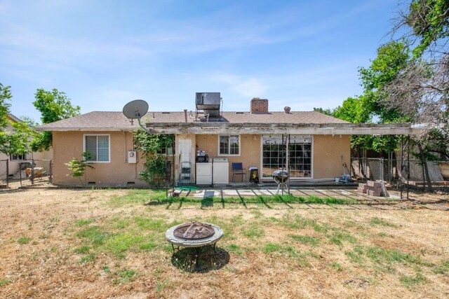 rear view of property with a fire pit, independent washer and dryer, a lawn, and a patio