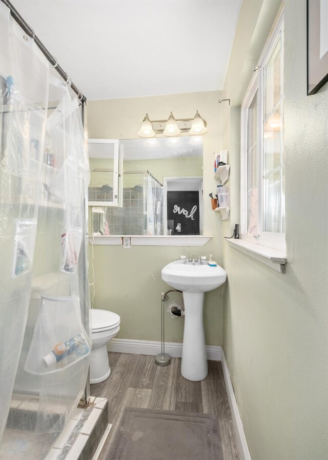 bathroom with toilet, a shower with shower curtain, and hardwood / wood-style floors