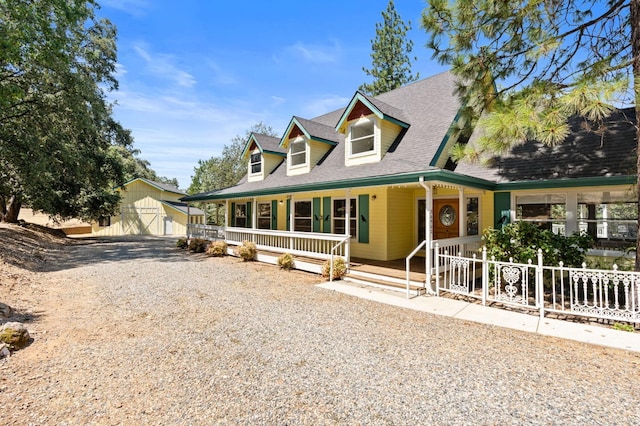 view of front of home featuring a porch, a garage, and an outdoor structure