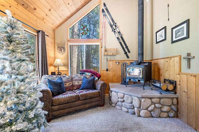 interior space with high vaulted ceiling, a wealth of natural light, a wood stove, and wooden walls