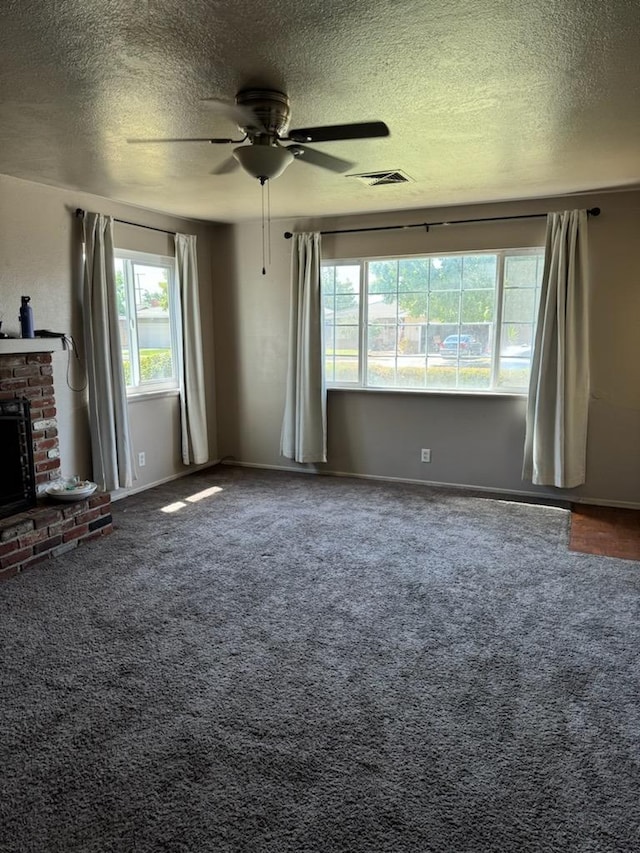 unfurnished living room with carpet, ceiling fan, a fireplace, and a textured ceiling