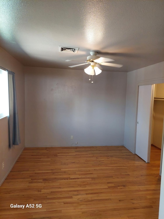 spare room featuring ceiling fan, a textured ceiling, and light wood-type flooring