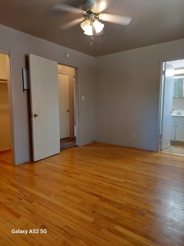 unfurnished bedroom with ensuite bath, ceiling fan, light hardwood / wood-style flooring, a spacious closet, and a closet