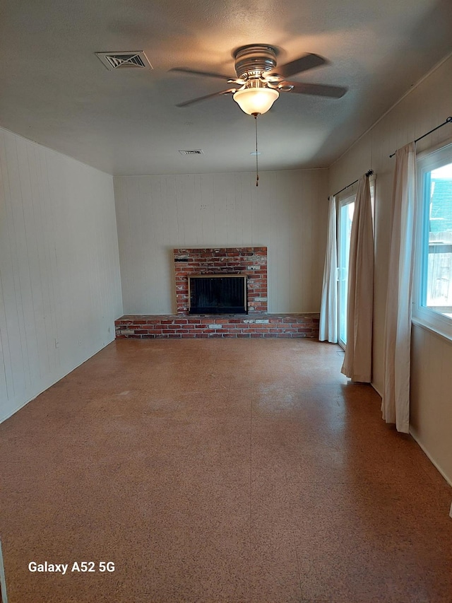 unfurnished living room featuring ceiling fan and a fireplace