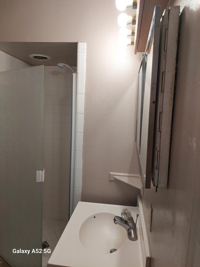 bathroom with sink and a shower with shower door