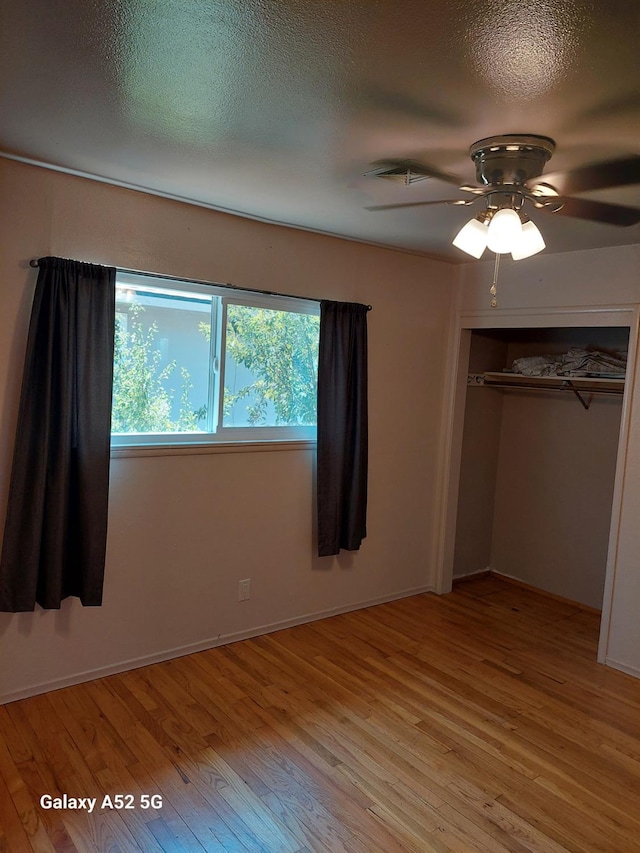 unfurnished bedroom featuring ceiling fan, a closet, a textured ceiling, and light hardwood / wood-style flooring