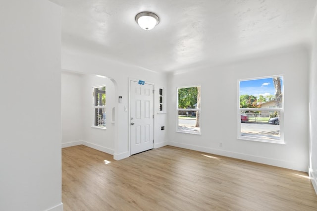 entrance foyer with light wood finished floors, baseboards, and arched walkways