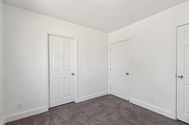 unfurnished bedroom featuring dark colored carpet and baseboards