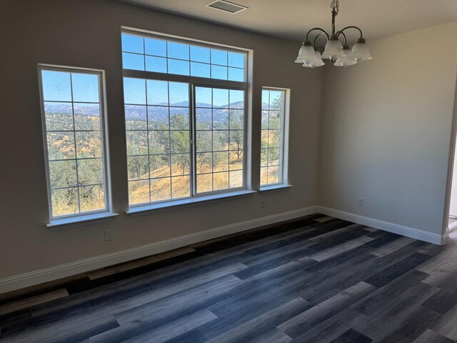 spare room with dark hardwood / wood-style floors and a chandelier