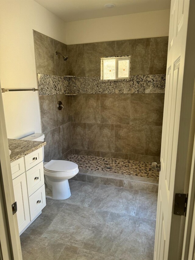 bathroom with tiled shower, vanity, and toilet