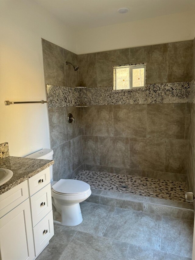 bathroom featuring vanity, toilet, and a tile shower