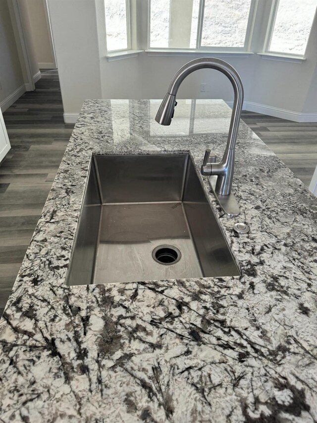 details with dark hardwood / wood-style floors, sink, light stone countertops, and white cabinetry