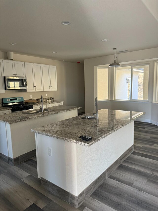 kitchen featuring pendant lighting, dark hardwood / wood-style flooring, sink, appliances with stainless steel finishes, and white cabinets