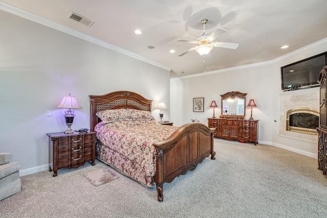 bedroom featuring light colored carpet, ceiling fan, ornamental molding, and a tiled fireplace