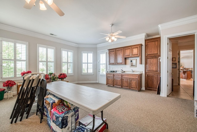 kitchen featuring ceiling fan, ornamental molding, and light carpet