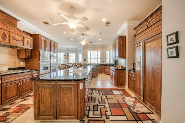 kitchen with crown molding, white appliances, sink, an island with sink, and ceiling fan